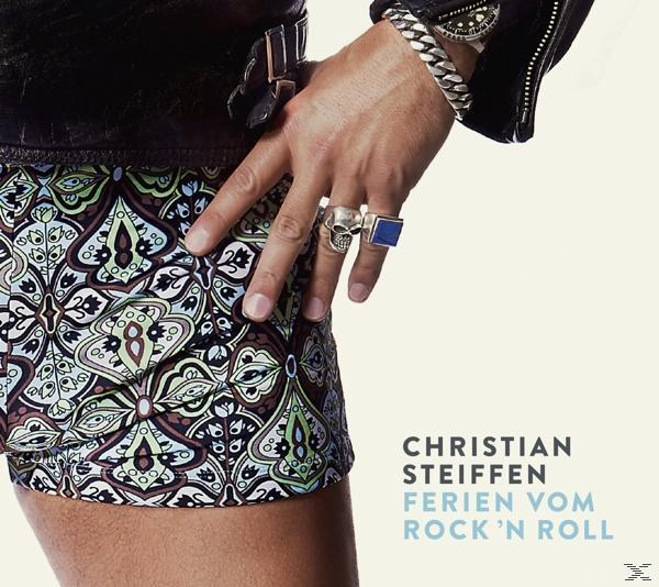 Albumcover mit der Hand eines Mannes mit Ringen und gemusterten Shorts.