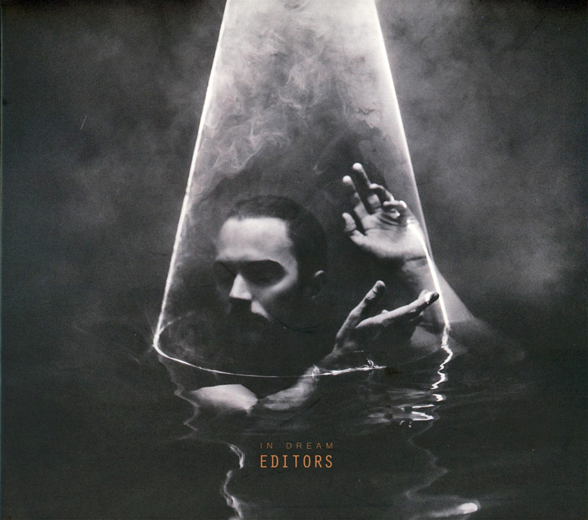Mann und Hände tauchen aus Wasser auf, in einem beleuchteten, rauchigen Kegel. Das Albumcover von Editors, 'In Dream'.
