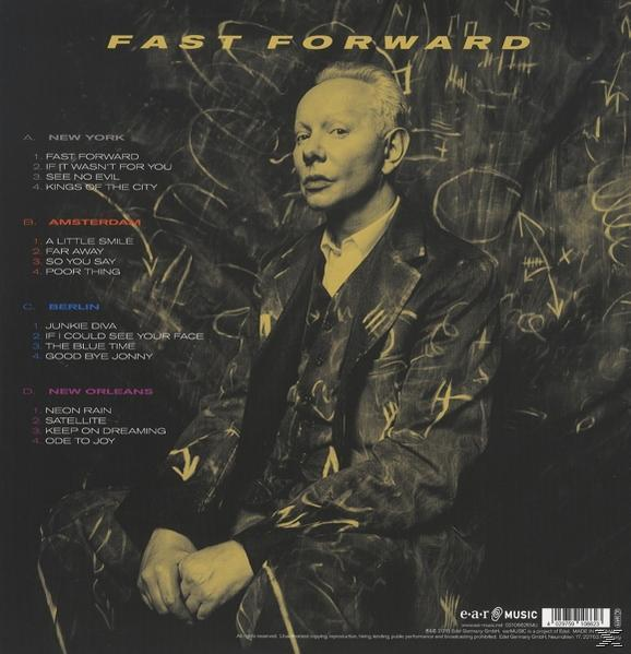 Albumcover mit einem Mann im Anzug, der sitzt. Text und Listen sind im Hintergrund sichtbar.