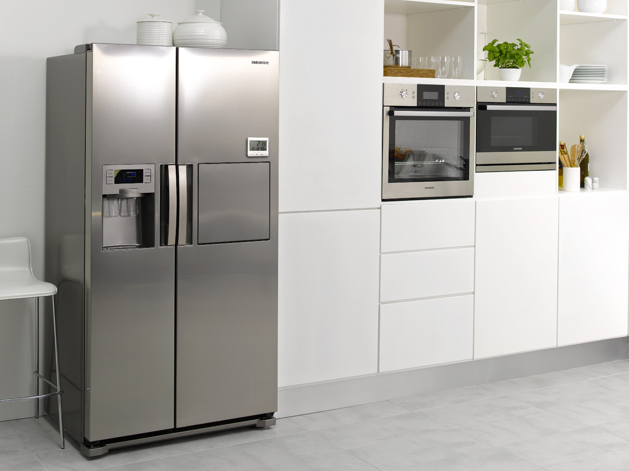 A stainless steel refrigerator next to a white kitchen cabinet with an oven and microwave.