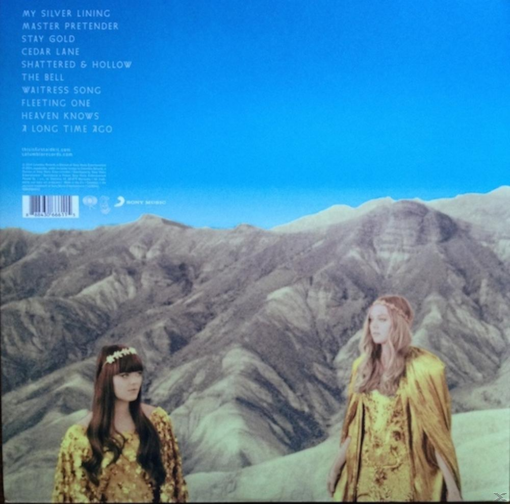Albumcover mit Text, zwei Frauen in goldenen Umhängen und einer bergigen Landschaft.