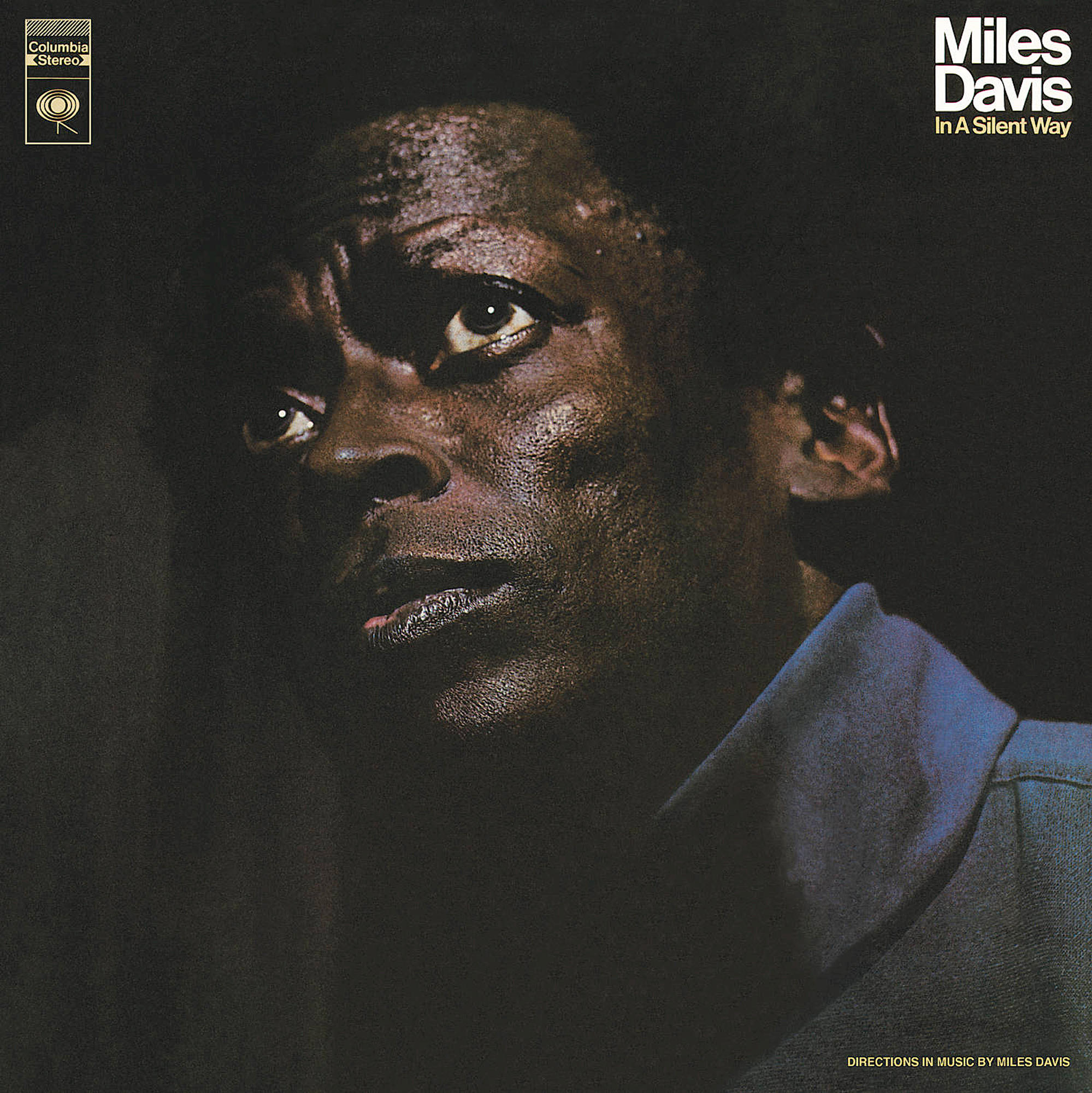 Album borító, Miles Davis, sötét, közeli portréban, kék galléros ingben.