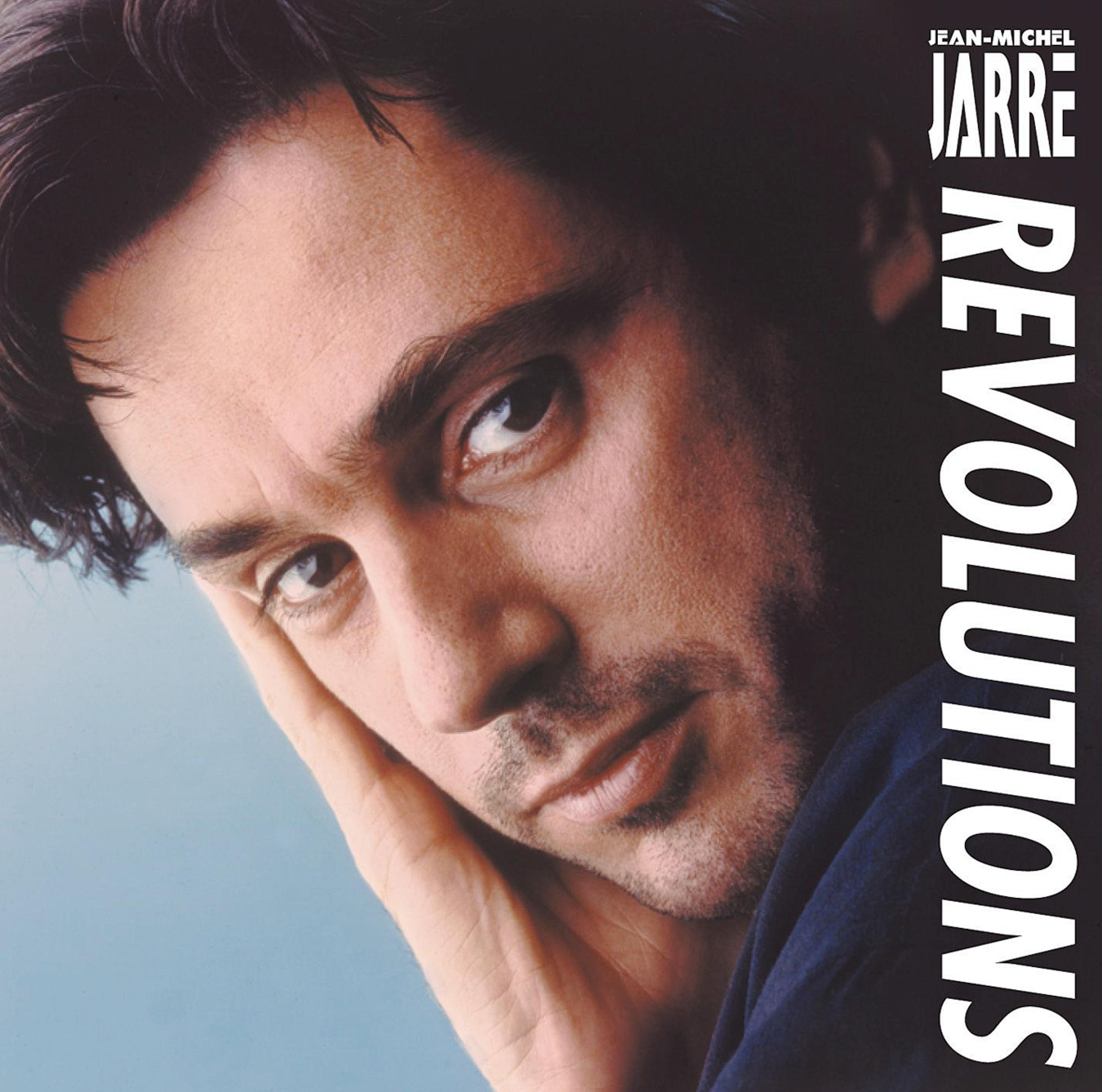Egy sötét hajú férfi közeli képe, az albumborítón fehér szöveg, Revolutions.