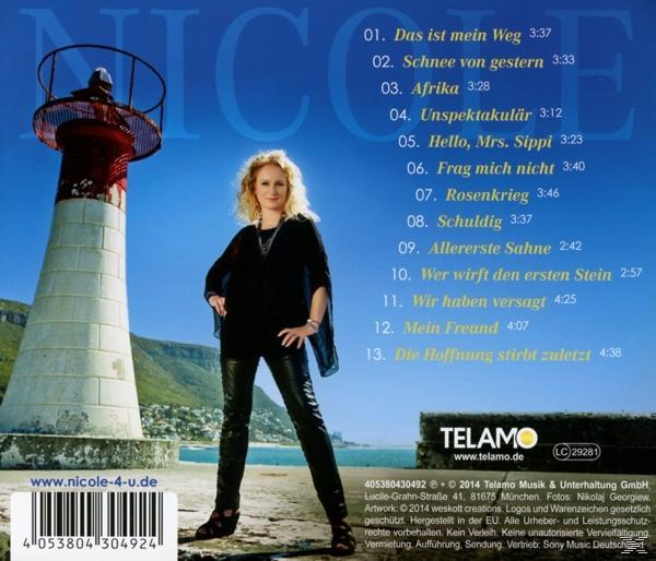 Eine Frau steht an einem Leuchtturm. Sie ist blond und trägt schwarze Kleidung. Der Hintergrund ist blau.