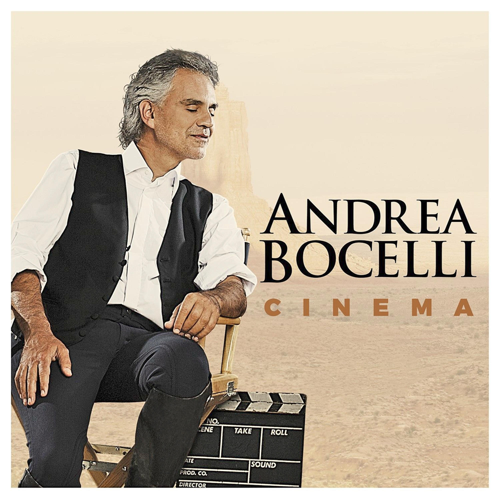 Andrea Bocelli egy filmcsapóval ül. A sivatagi háttérben a 'Cinema' felirat látható.