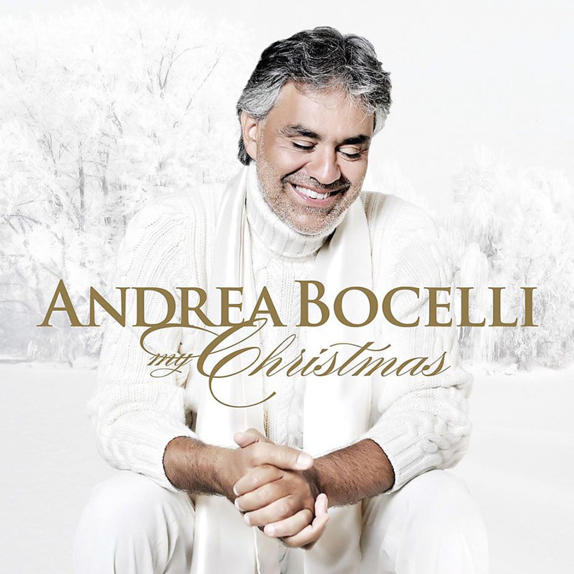 Andrea Bocelli vor schneebedecktem Hintergrund. Er trägt einen weißen Pullover und Schal.