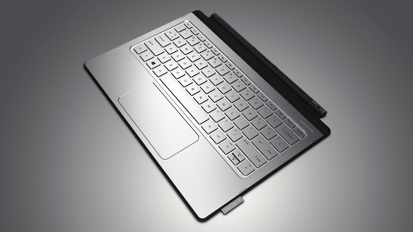 Eine silberne Laptop-Tastatur und ein Trackpad aus der Vogelperspektive auf grauer Oberfläche.