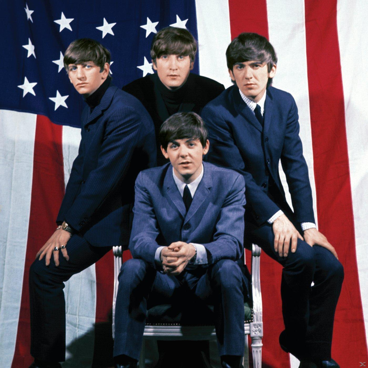 A Beatles az amerikai zászló előtt pózol, négy férfi öltönyben, formális pózban.
