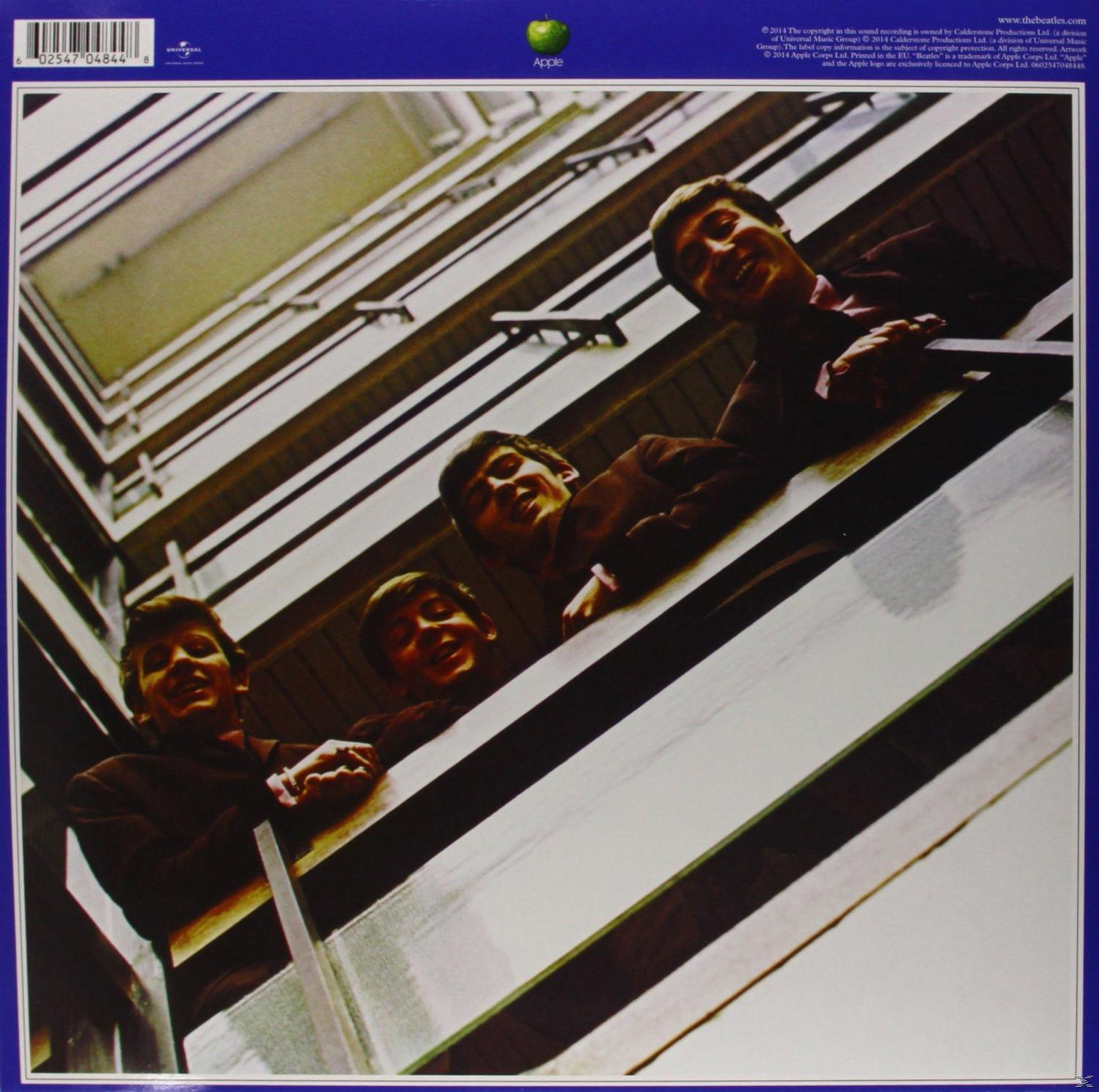 Das Beatles-Albumcover. Vier Männer in Anzügen blicken von einer Treppe herunter.