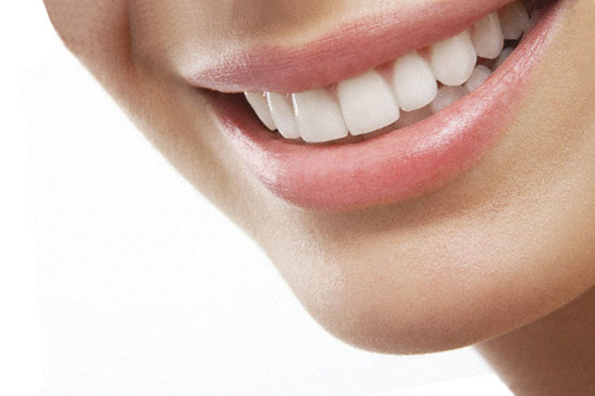 Nahaufnahme des Mundes einer lächelnden Person. Weiße Zähne und rosa Lippen. Der Fokus liegt auf den Zähnen.