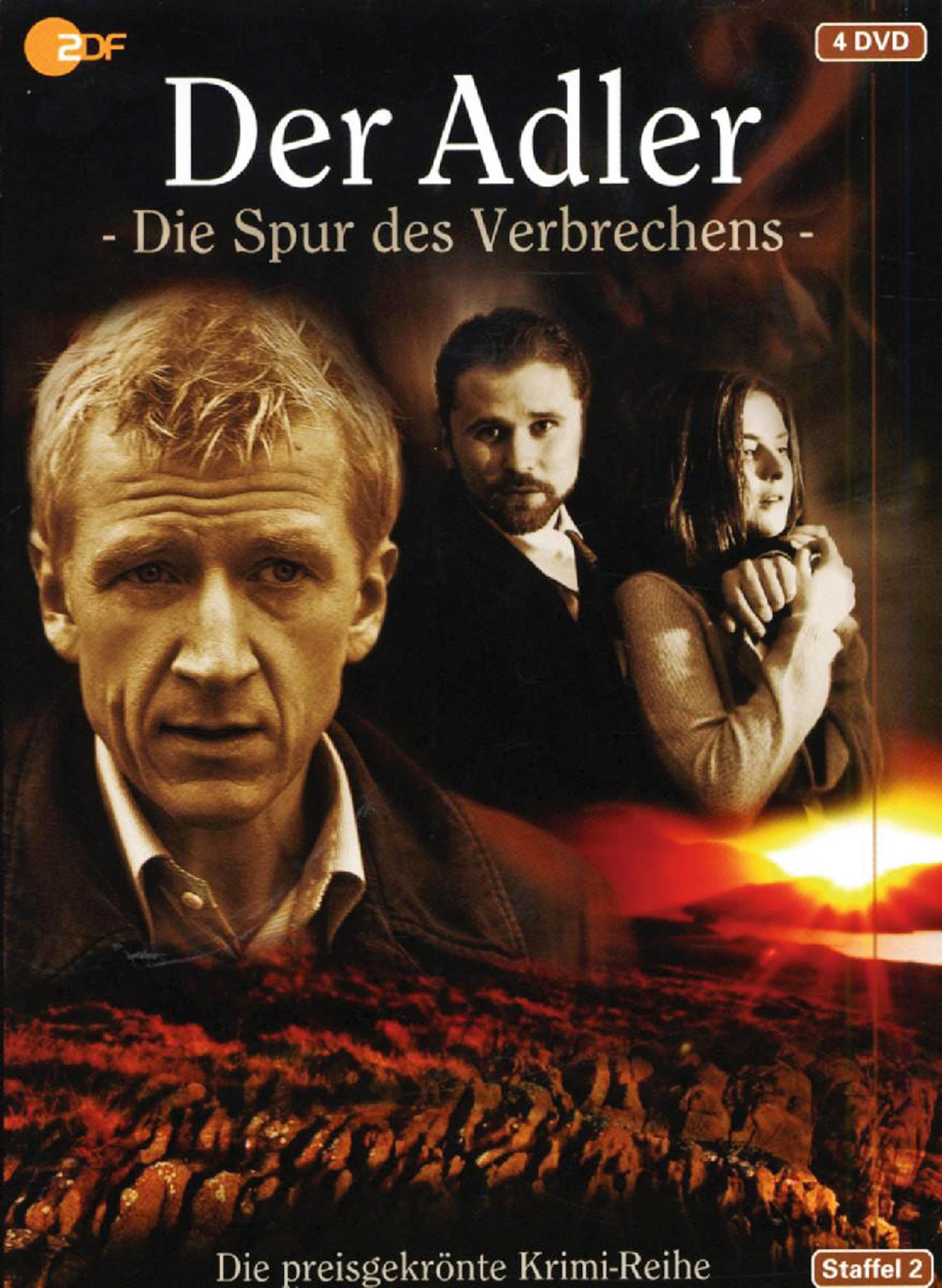 DVD-Cover, ein Mann starrt nach vorne, zwei Personen im Hintergrund. Titel: Der Adler.