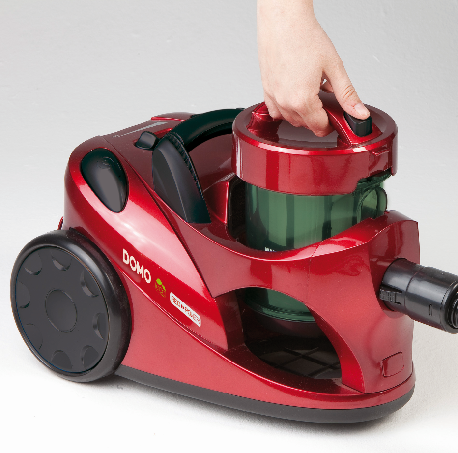 Aspirateur rouge, main tenant le couvercle, roues noires, fond blanc.