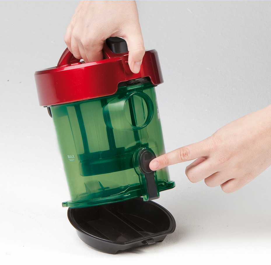 Mains tenant un aspirateur vert et rouge. Doigt pointant le bouton.