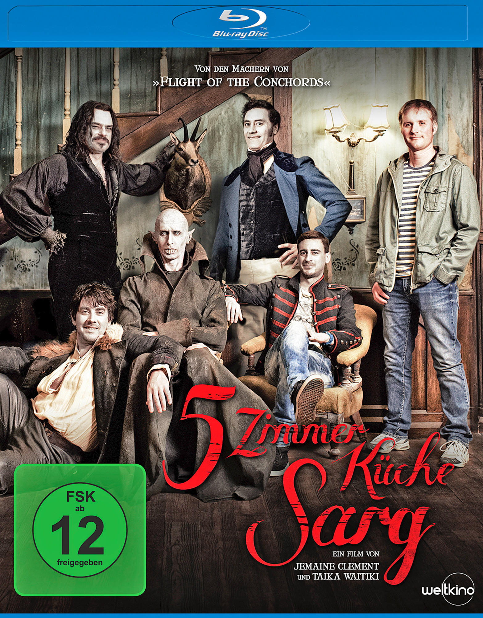 Filmcover mit einer Gruppe von Männern. Die Männer befinden sich in einem Innenraum. Text auf Deutsch.
