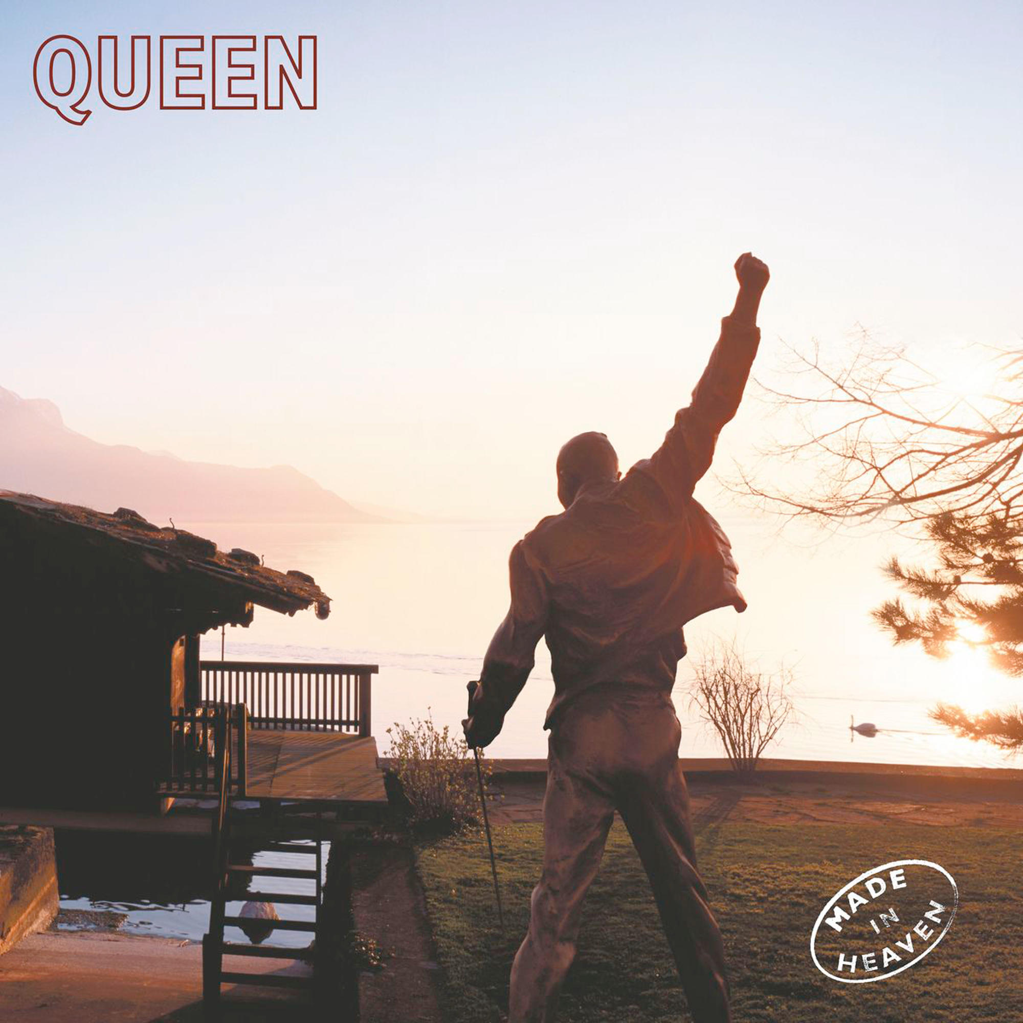 Albumcover: Eine Statue von Freddie Mercury mit erhobener Faust, mit Blick auf einen See bei Sonnenuntergang.