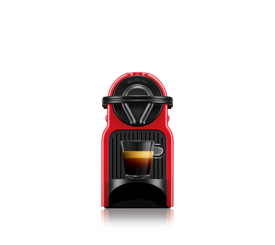 Eine rote Nespresso-Kaffeemaschine mit einem Glas, das Kaffee enthält. Weißer Hintergrund.