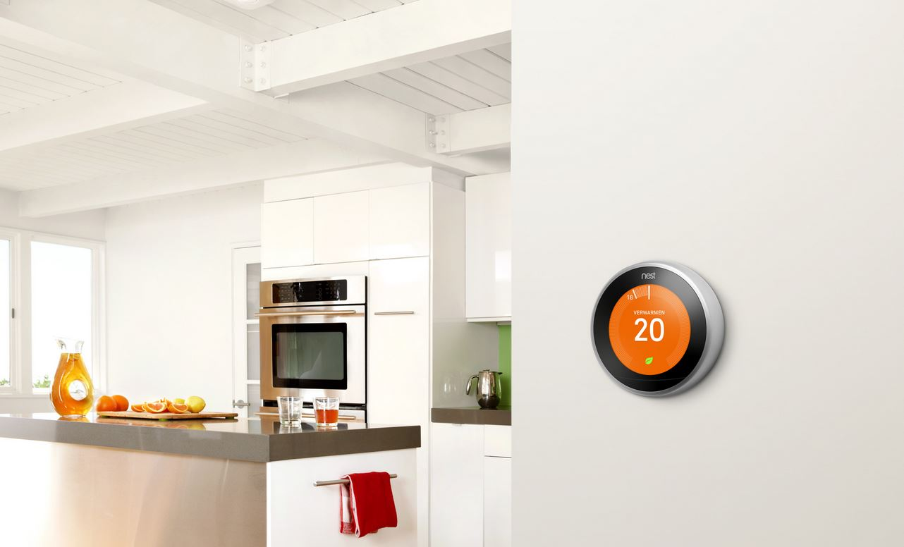 Een Nest thermostaat op een witte muur, met een keukeneiland op de achtergrond.