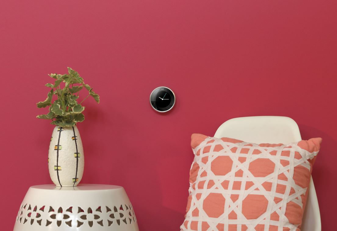 Kamer met een roze muur, een klok, een vaas en een kussen op een stoel. Minimalistische esthetiek.