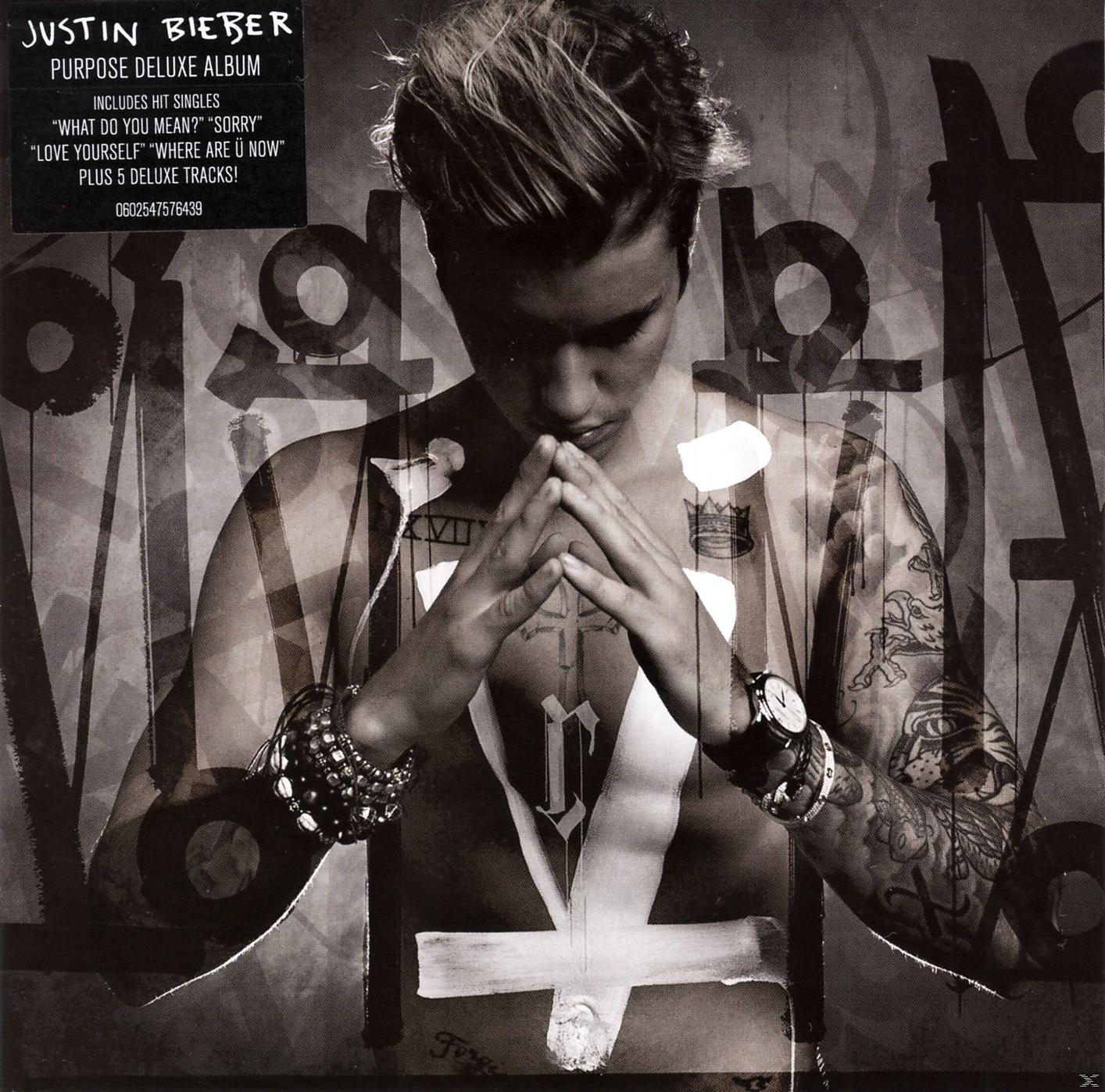 Justin Bieber albumhoes, ontbloot bovenlichaam met tatoeages, handen gevouwen, kruis op borst.