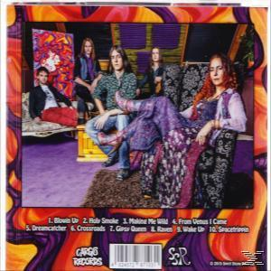 Albumcover mit einer Band mit langen Haaren in einem Raum mit farbenfroher Einrichtung. Die Band sitzt.