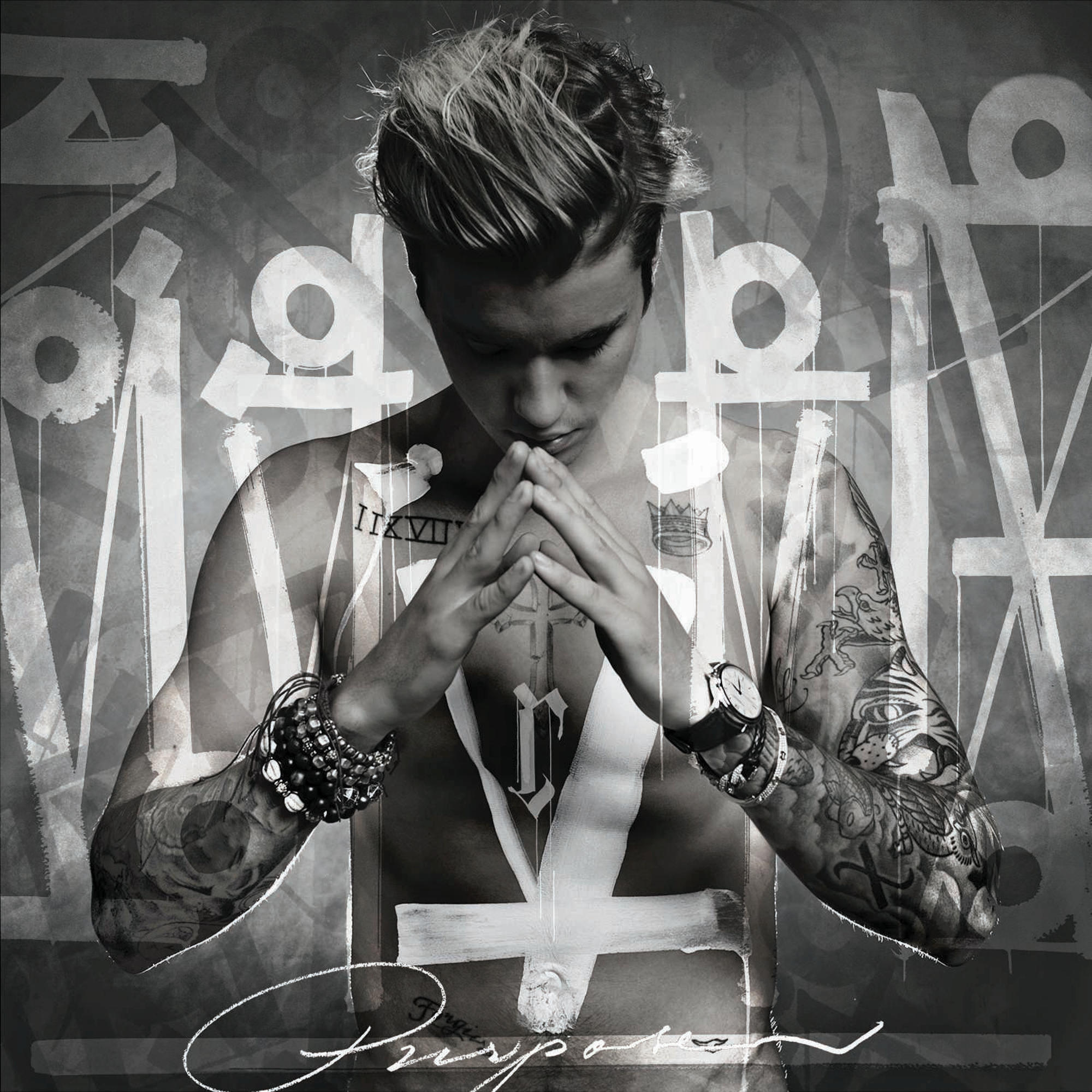 Justin Bieber met tatoeages, gevouwen handen en een kruis op zijn borst.
