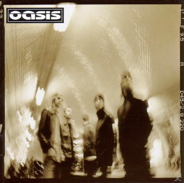 Albumcover: verschwommenes Foto einer Band, die in einem Tunnel geht, mit dem Bandnamen 'Oasis'.
