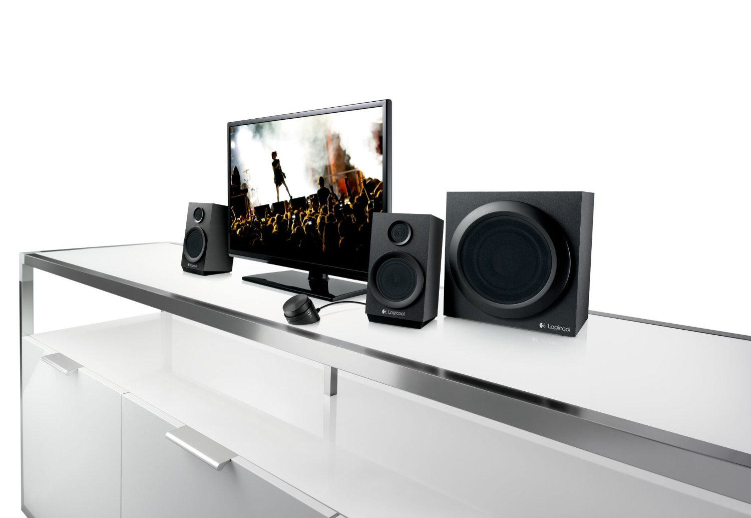 Beyaz bir yüzey üzerinde bir monitör, iki hoparlör, bir subwoofer ve bir fare bulunan bilgisayar kurulumu.