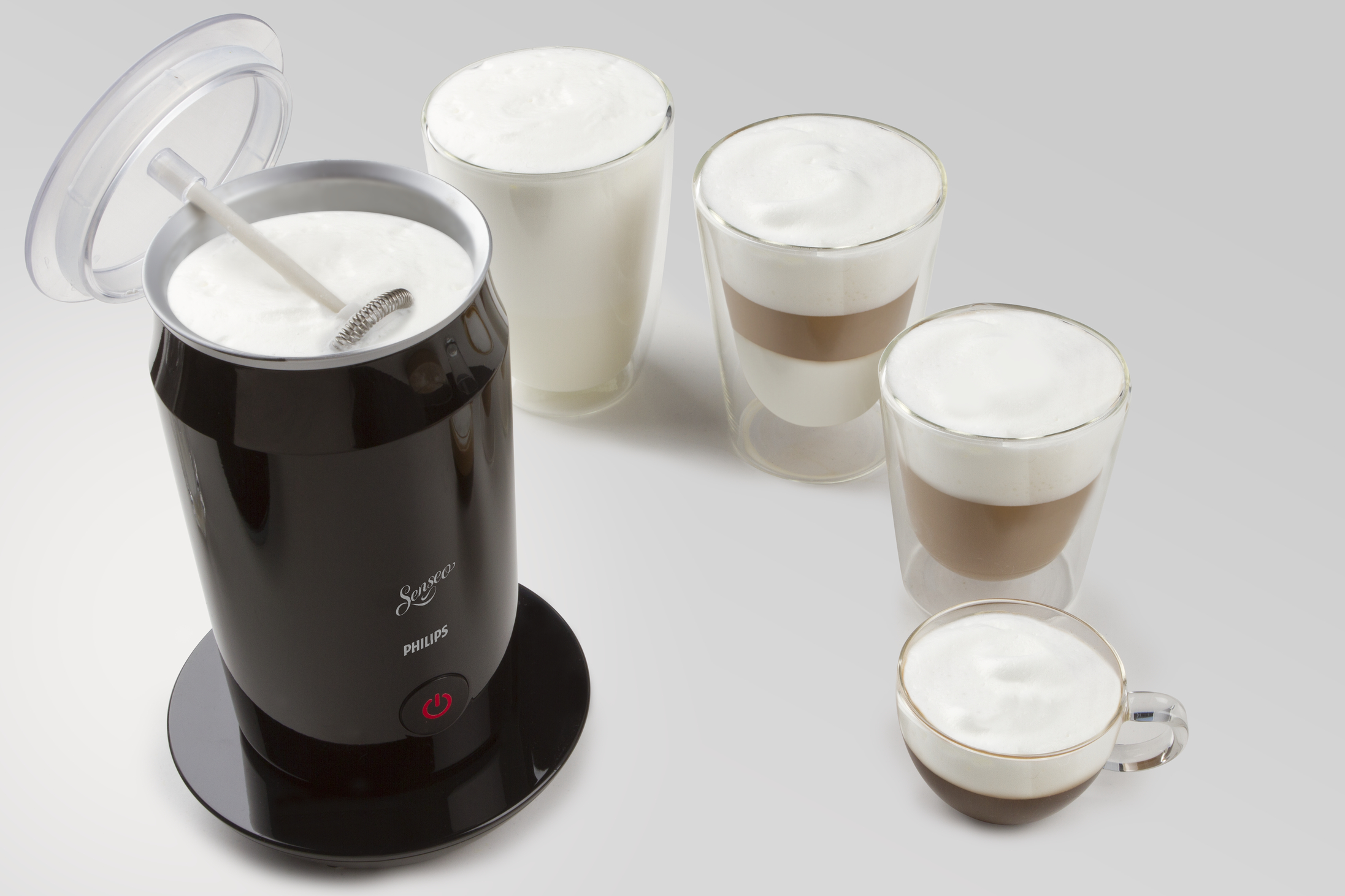Een zwarte Philips melkopschuimer met schuimbekers, op een witte achtergrond.