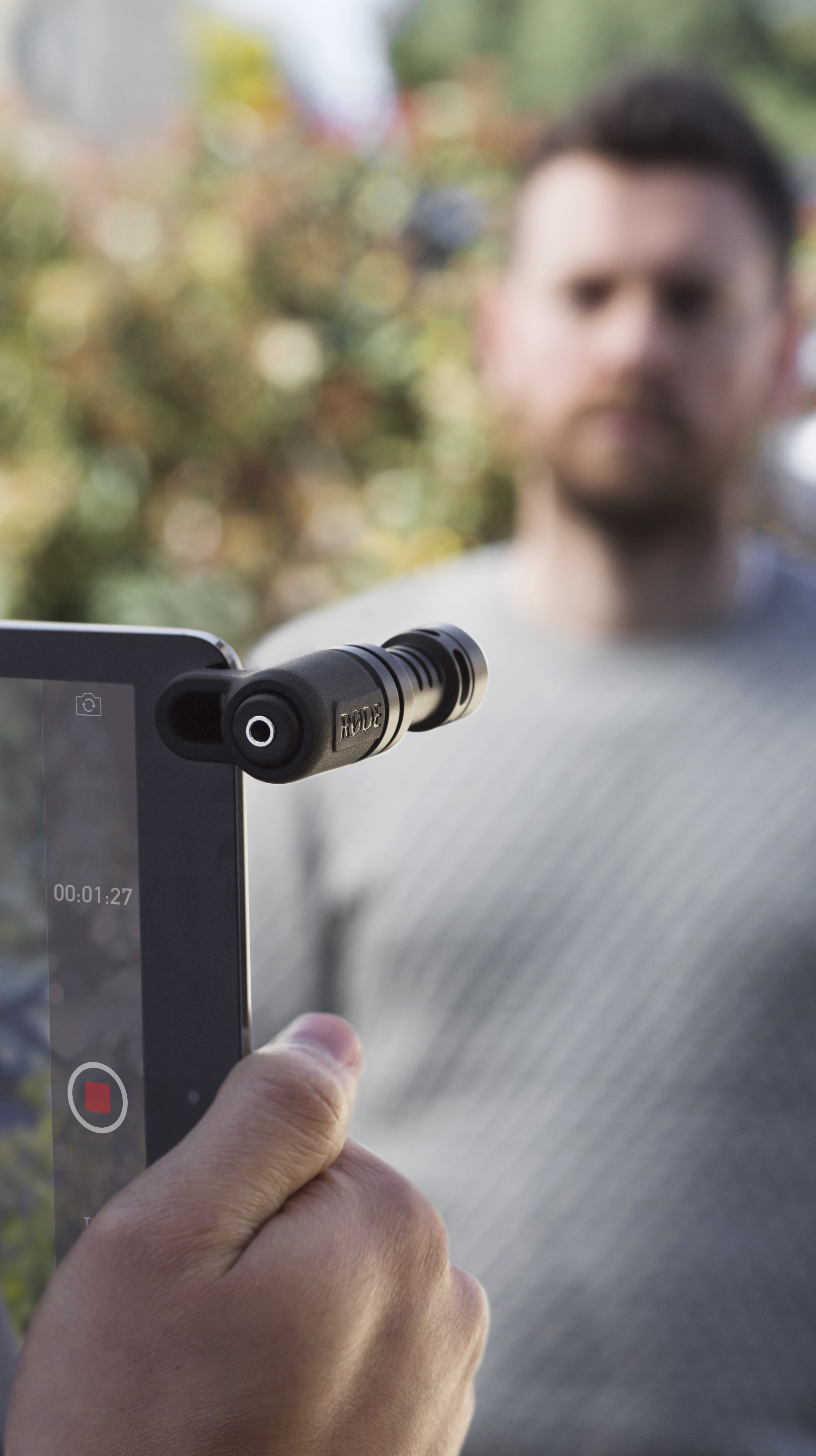Ein Smartphone mit Mikrofon wird auf eine unscharfe Person gerichtet.