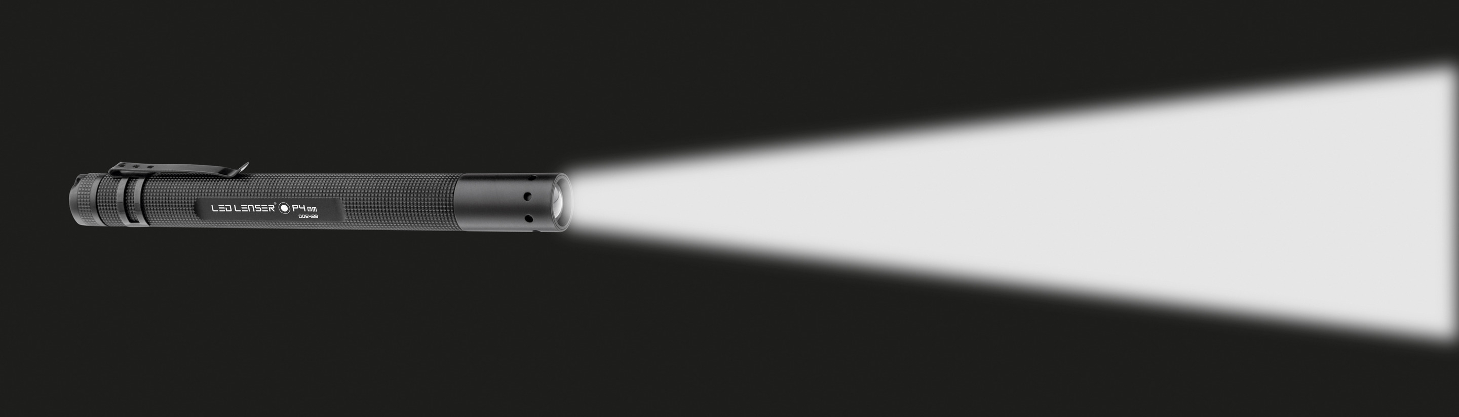 Eine schwarze LED Lenser-Taschenlampe auf dunklem Hintergrund. Der Lichtstrahl ist sehr hell und weiß.