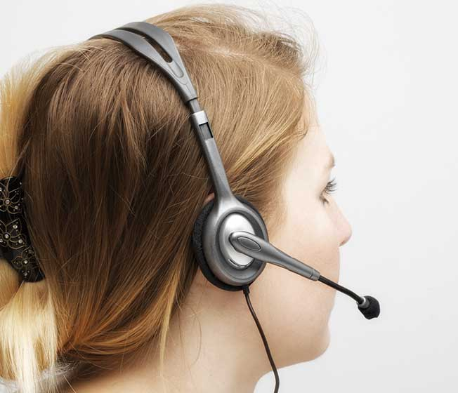 Blonde woman wearing a gray headset. Side profile view. White background. Head and shoulders.