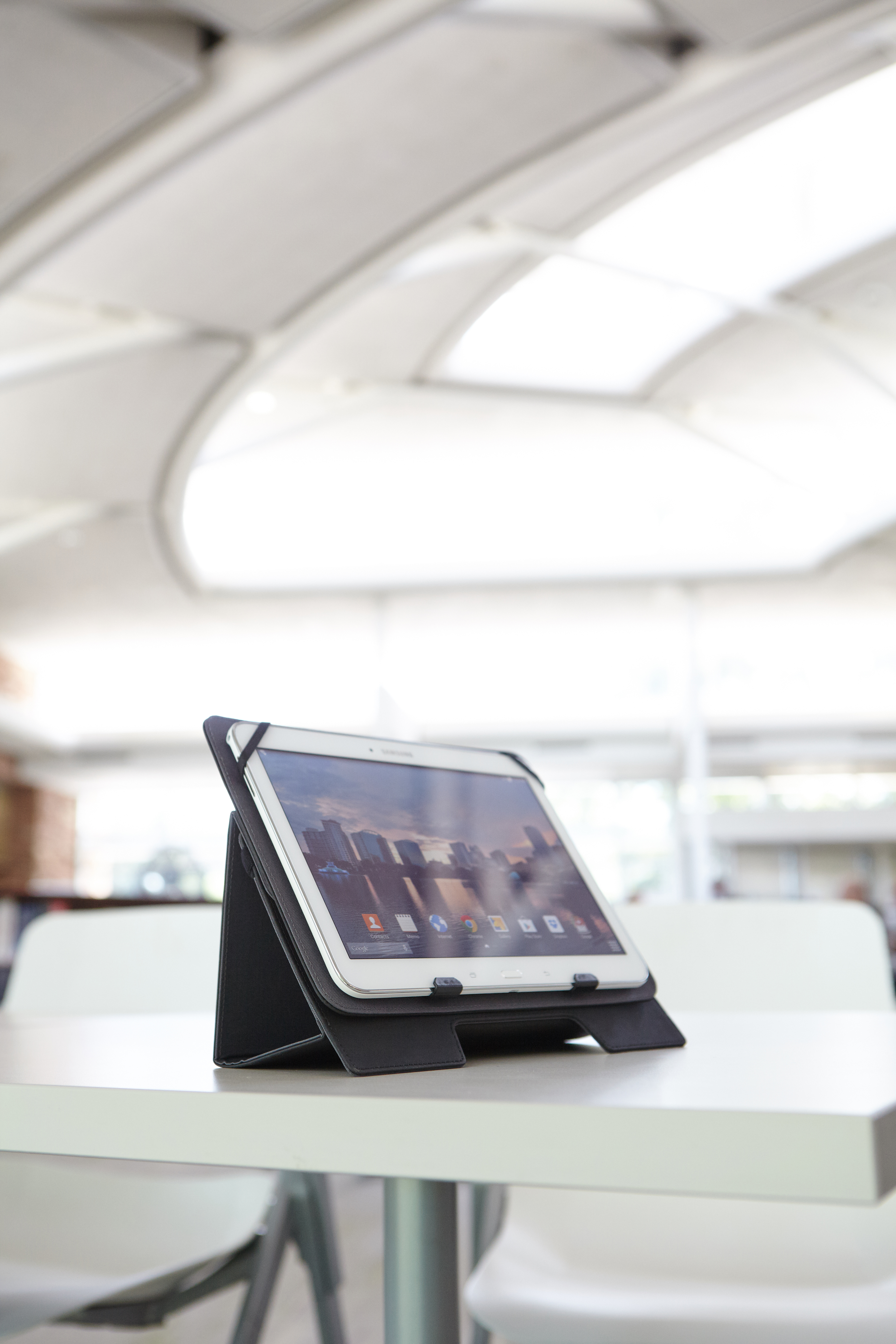 Tablet op een witte tafel. Het scherm toont een stad. De achtergrond is een wazig kantoor.