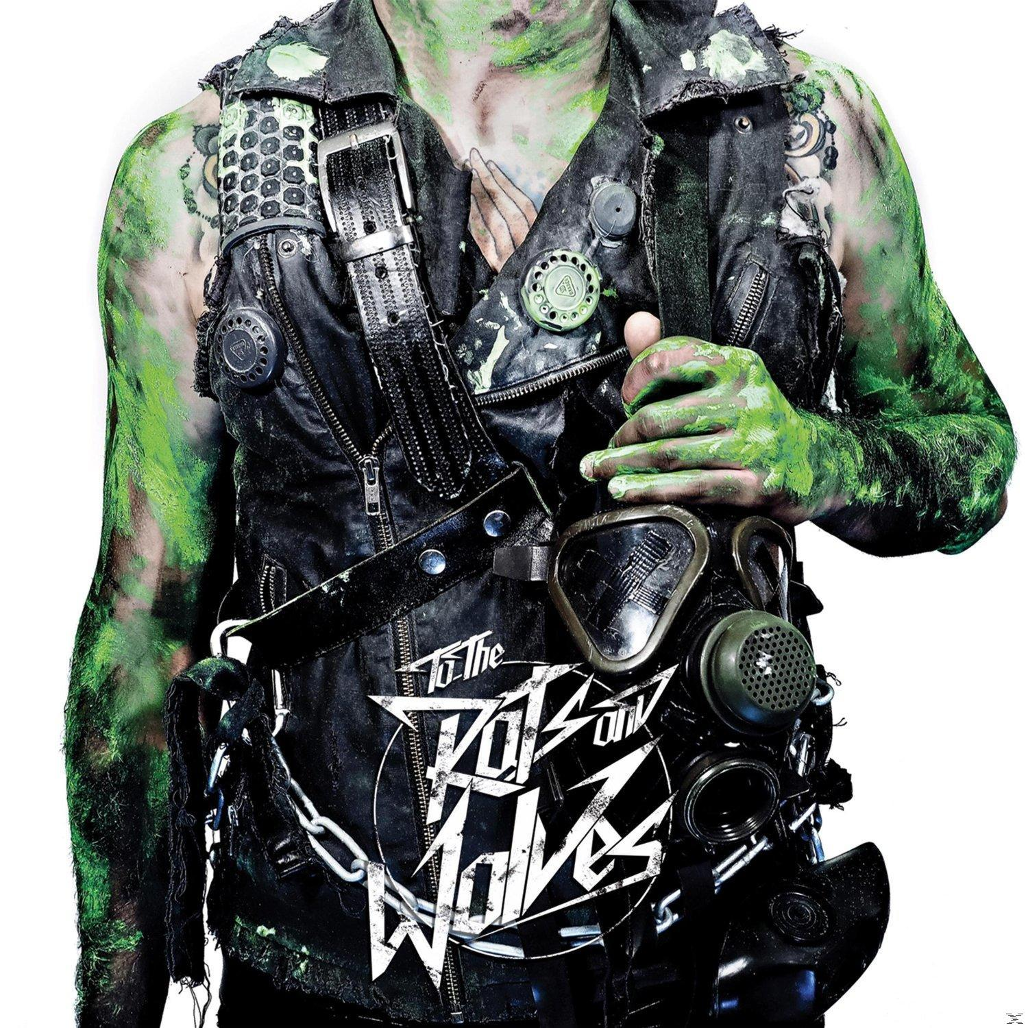 Eine Person mit grüner Farbe, trägt eine schwarze Weste mit Gasmaske, der Text "To The Wolves" steht auf der Weste.