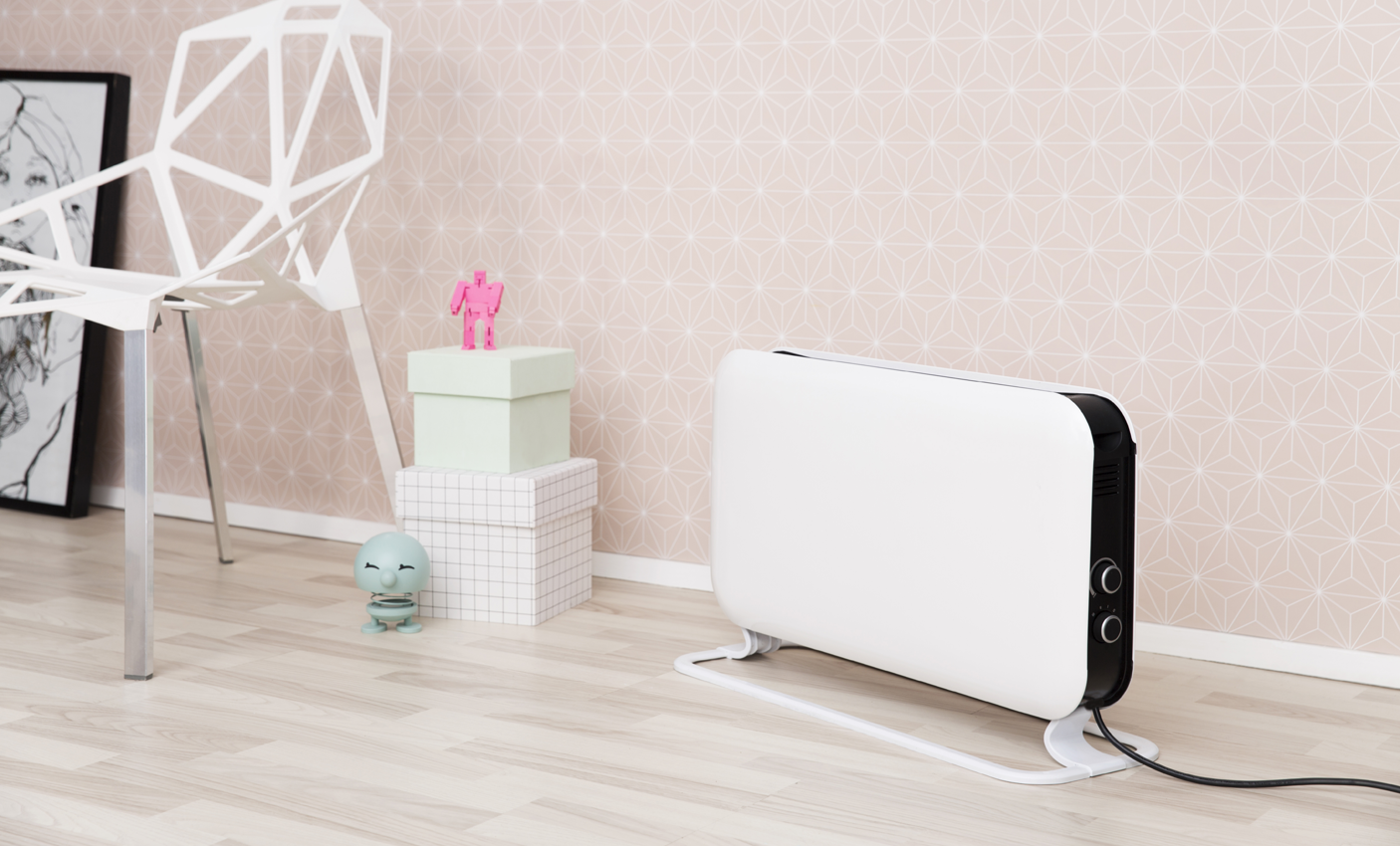 White heater in a room with pink wallpaper and a chair.