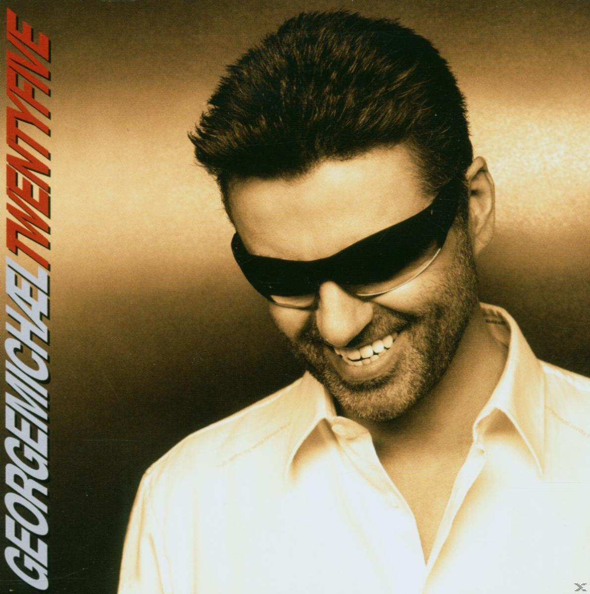 George Michael mosolyog, napszemüveget visel, barna háttér előtt.
