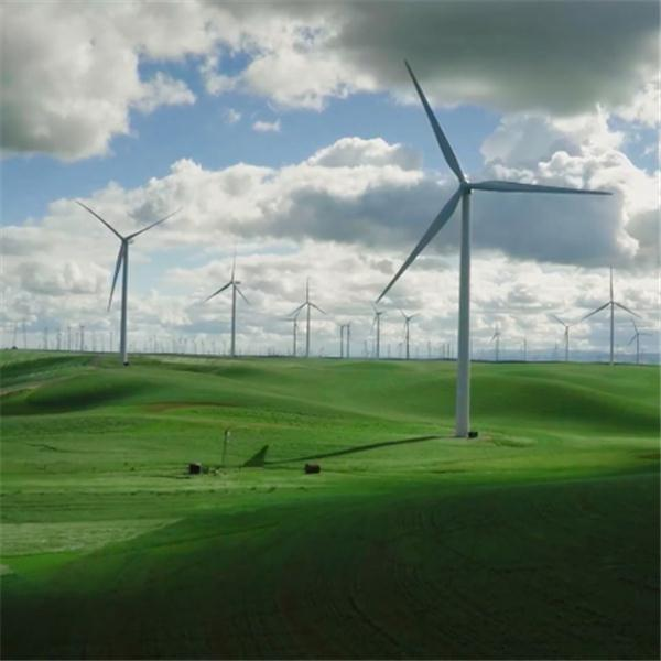Windturbines op groene heuvels onder een bewolkte blauwe lucht. Verschillende turbines zijn zichtbaar, wat duidt op een windmolenpark.