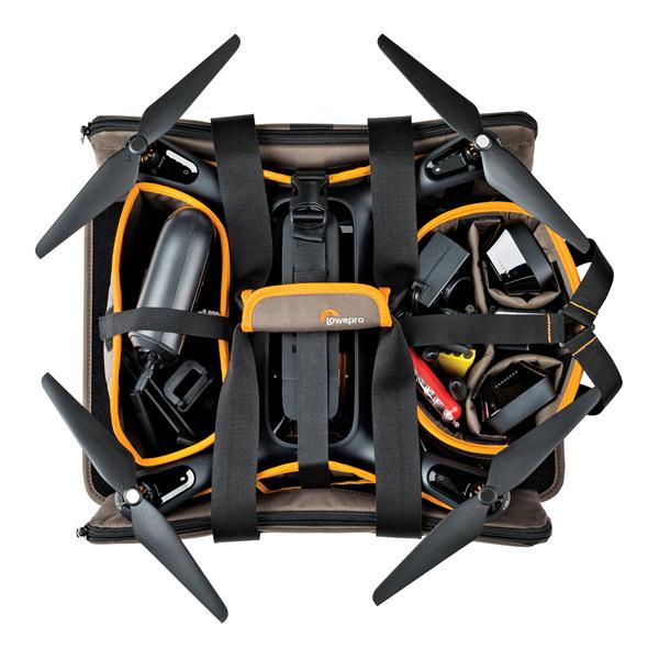 Drone in een bruine tas. Tas heeft compartimenten voor apparatuur en propellers. Oranje accenten. Zwarte riemen.