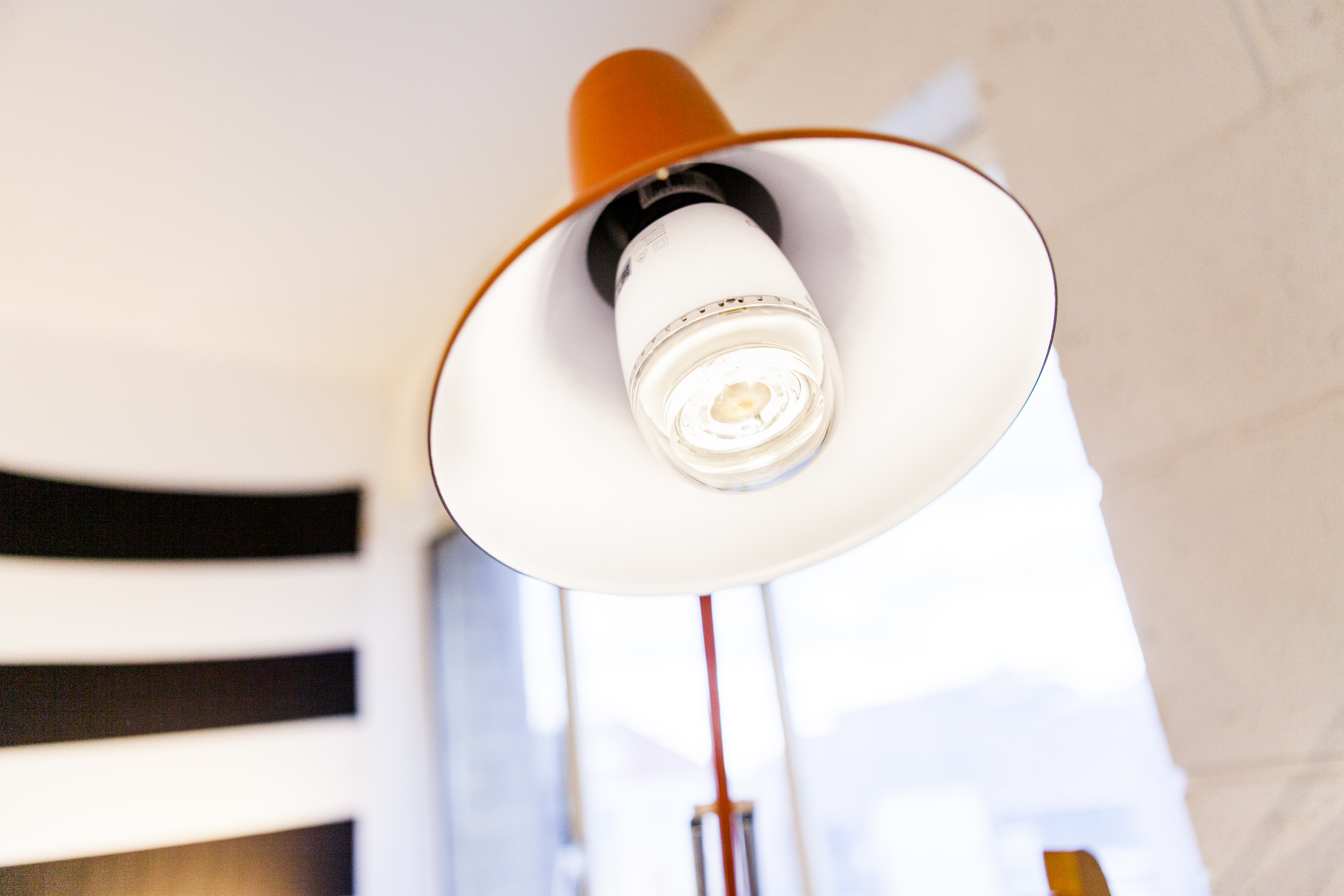 An orange lamp is positioned from a low angle. The lamp has a white interior, and a lightbulb is visible.