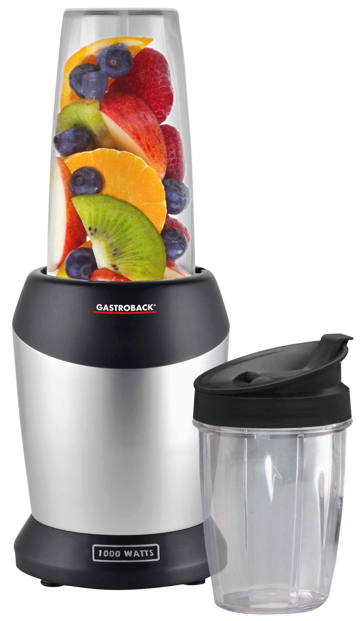 Mixer mit Früchten: Orangen, Kiwi, Beeren und rote Apfelscheiben in einem transparenten Becher und ein schwarzer Becher daneben.