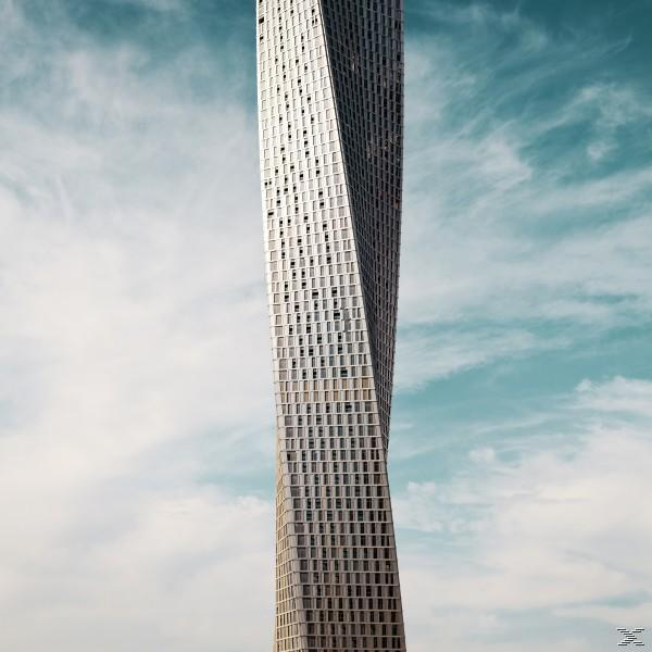 Verdrehtes Hochhaus vor blauem Himmel. Das Gebäude ist weiß mit vielen Fenstern.