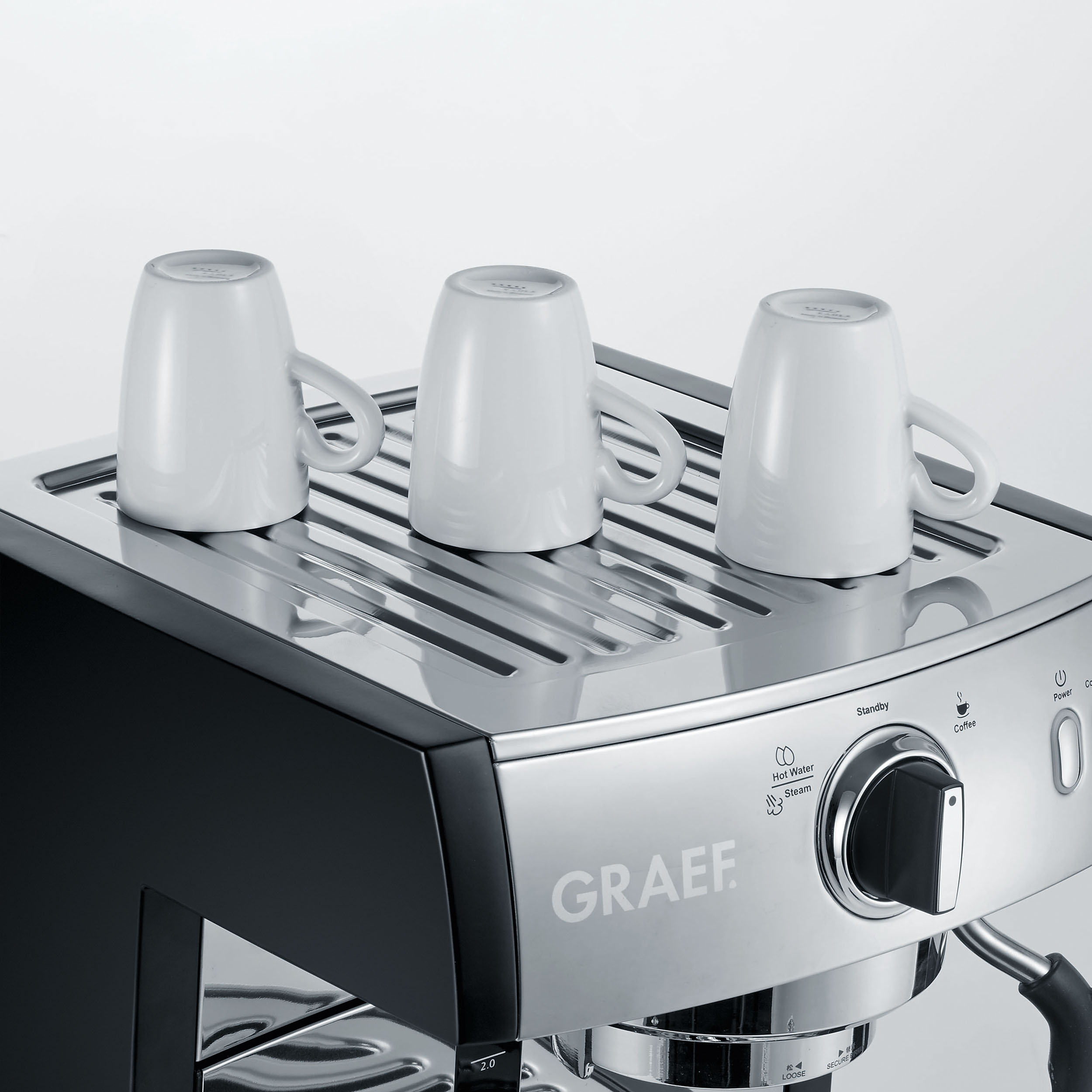 Eine Espressomaschine mit drei weißen Tassen auf der Oberseite. Grau und Schwarz.