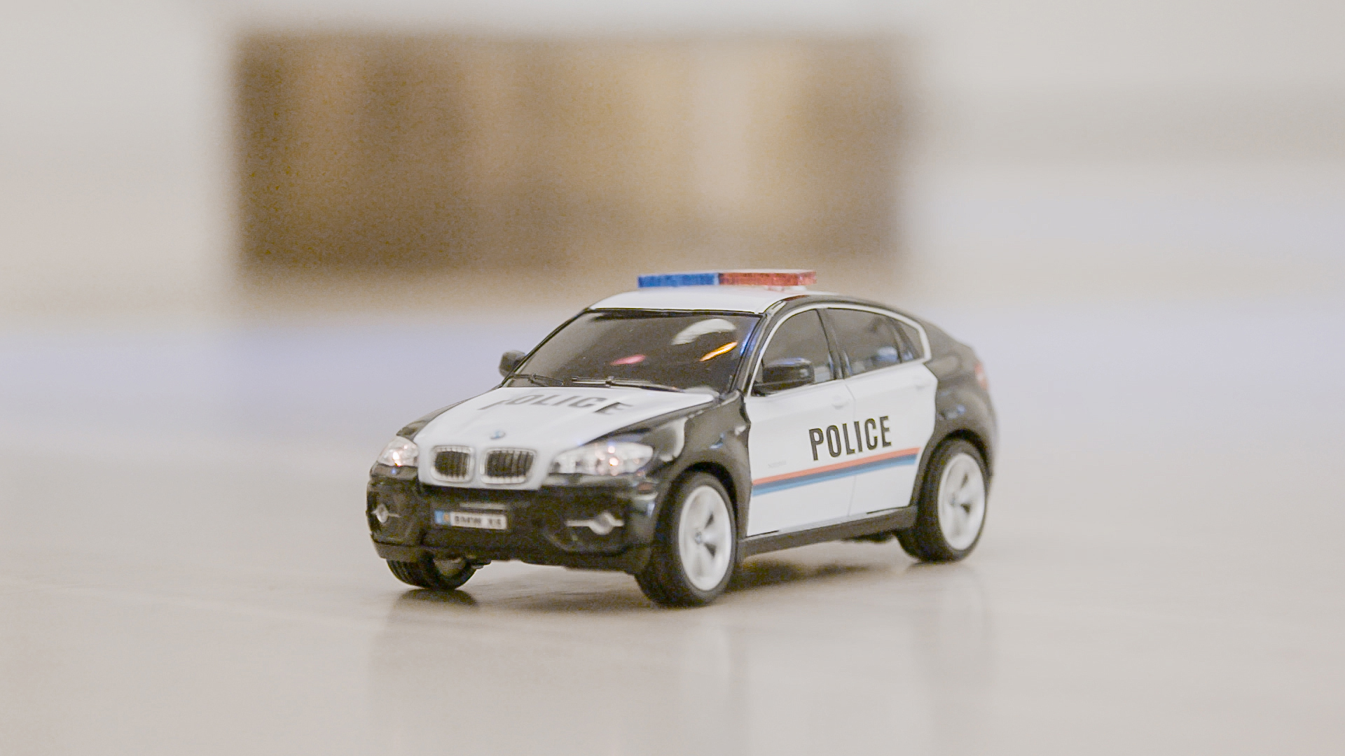 Ein Spielzeug-Polizeiauto, schwarz und weiß, mit blauen und roten Lichtern auf einer weißen Oberfläche.