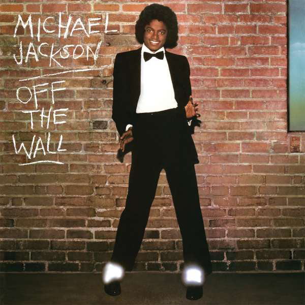 Michael Jackson téglafal előtt áll, öltönyt és csokornyakkendőt visel, felül szöveggel.