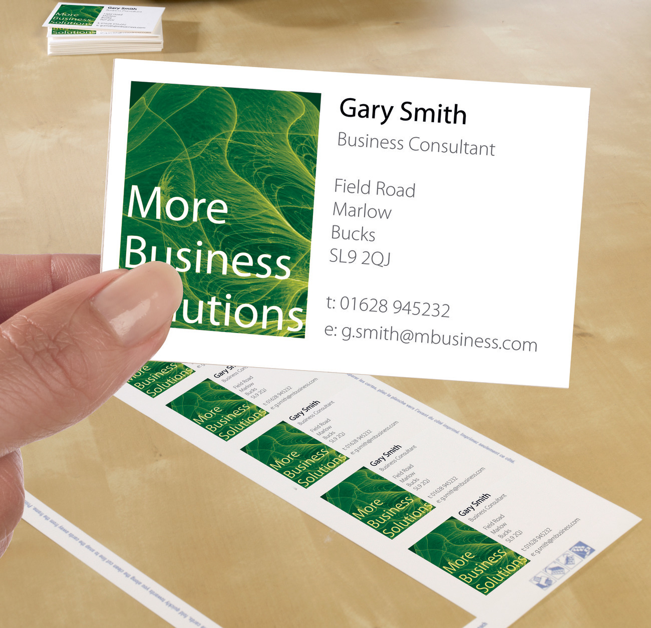 Visitenkarten werden gehalten, mit den Worten 'More Business Solutions'.