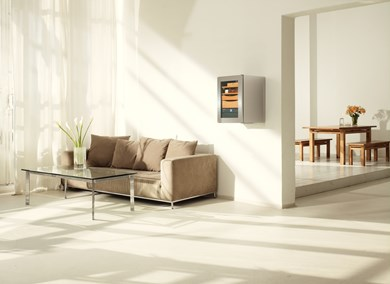 Modernes Wohnzimmer. Weiße Wände, braunes Sofa und ein Weinkühler an der Wand. Sonnenlicht durchs Fenster.