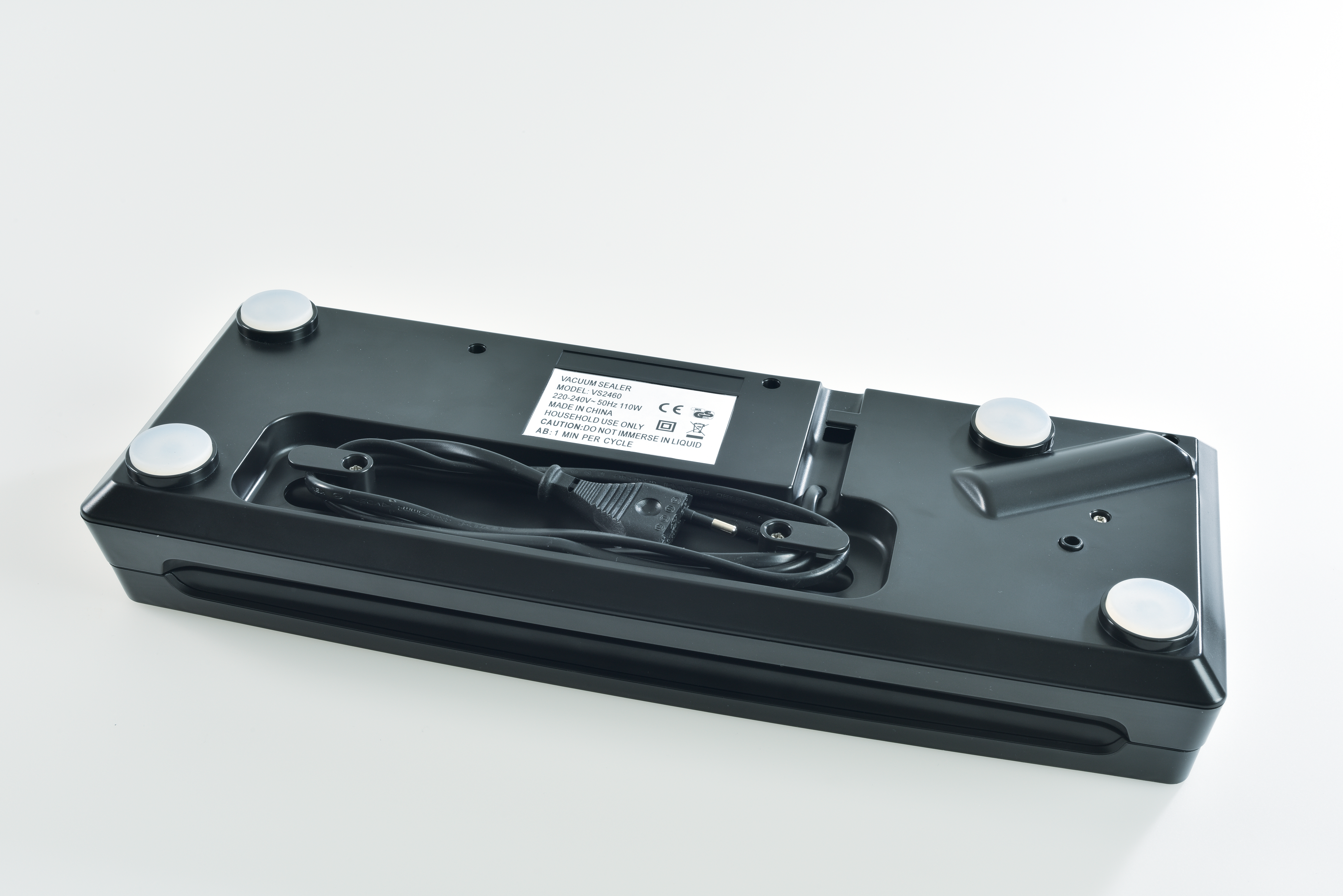 A black vacuum sealer on a white surface. It has a power cord and white rubber feet. A label shows product details.