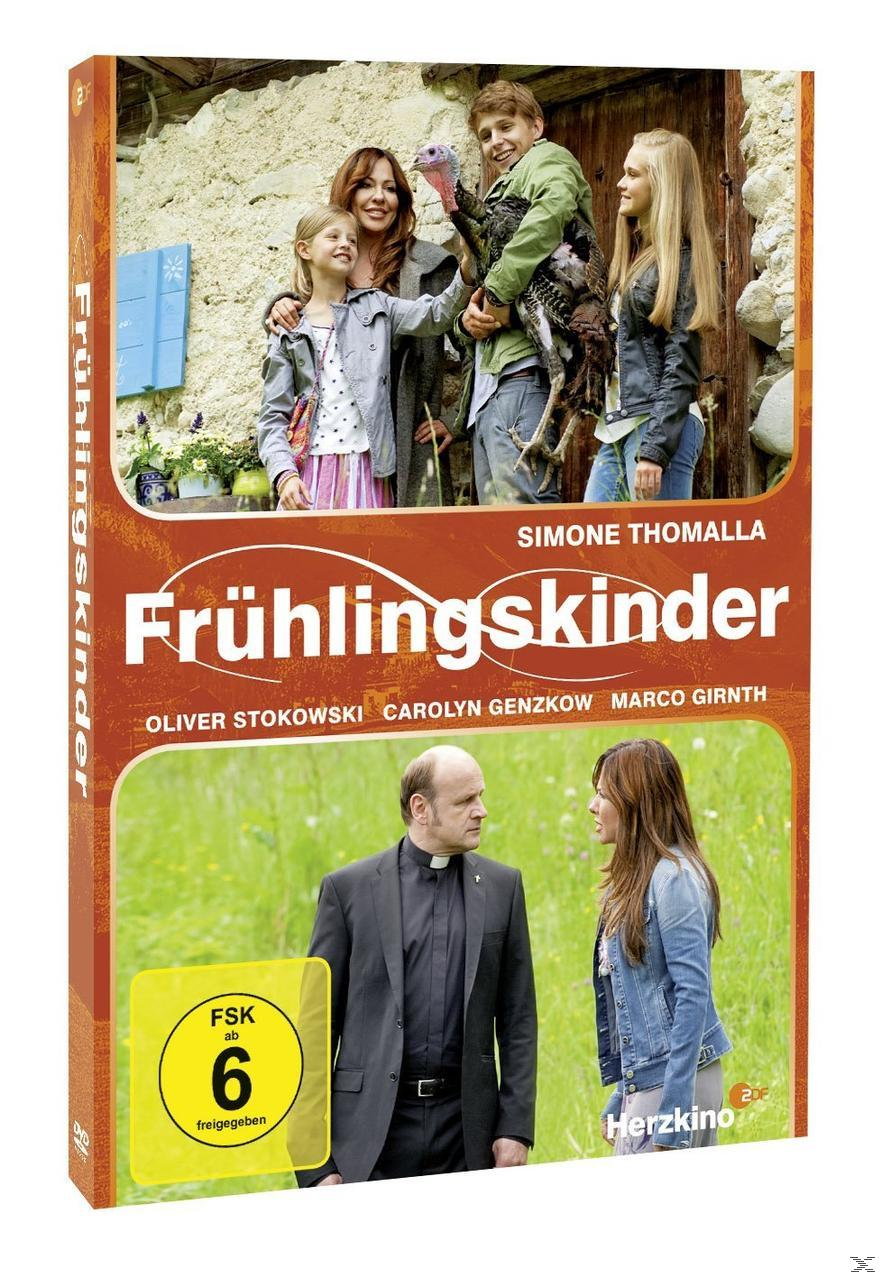DVD-Cover von "Frühlingskinder". Eine Familie mit Truthahn steht an einem Steingebäude. Unten stehen ein Priester und eine Frau einander gegenüber.