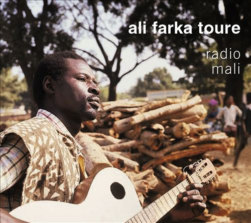 Férfi fehér gitáron játszik, farönkök a háttérben, Ali Farka Toure album borítója.