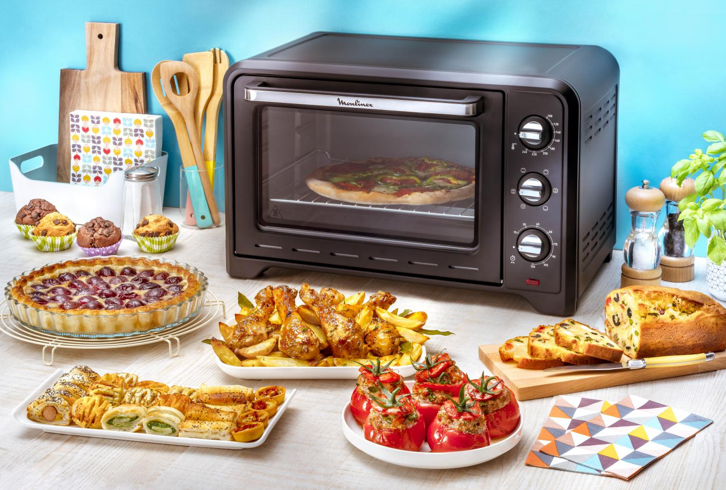 A kitchen scene with a black oven filled with pizza. Various dishes of food are displayed.
