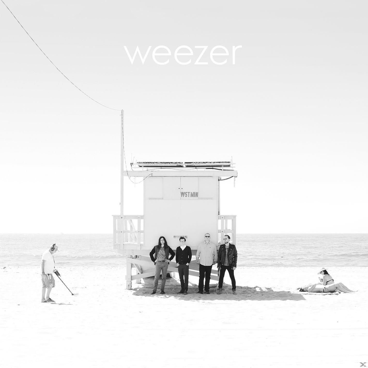 Pochette de l'album Weezer. Le groupe se tient devant une tour de sauveteur sur une plage, avec une personne détectant le métal.